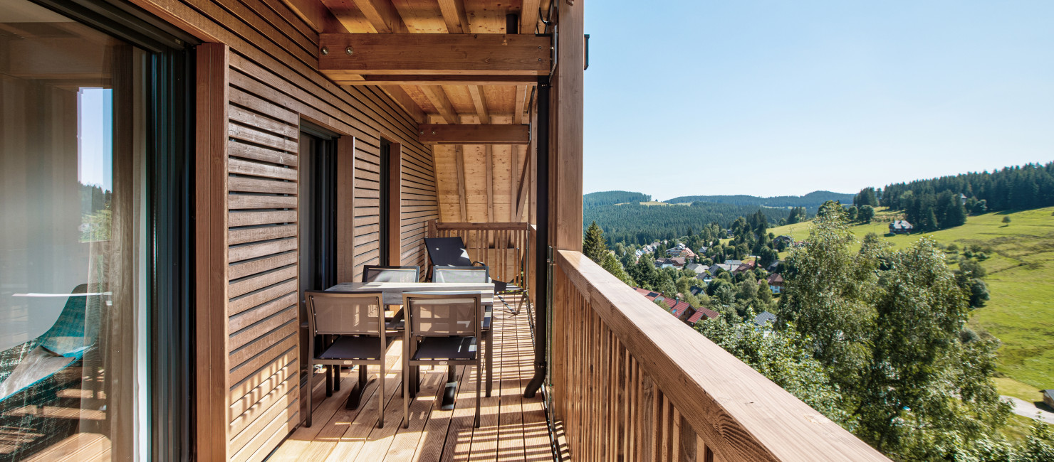 Blick über eine Doppelbett und den Wohn- und Essbereich des Apartments